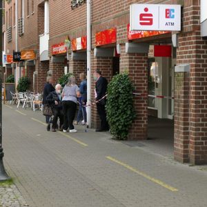 Kunden stehen vor der Tür einer Haspa-Filiale, die mit rot-weißem Absperrband gesperrt ist