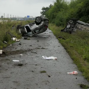 Zwei Autos liegen kopfüber einige Meter neben der Autobahn
