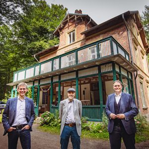 Foto: Drei Männer stehen vor einer Landhausvilla
