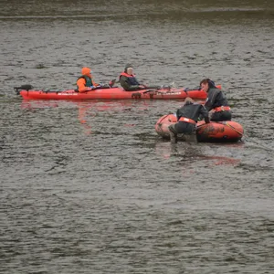 Feuerwehrtaucher kämpfen sich durch den Schlick zu dem steckengebliebenen Kajak vor.