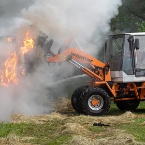 Mithilfe eines Radladers luden die Feuerwehrkräfte die brennenden Strohballen ins Freie.