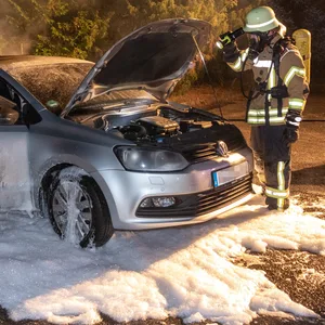 Die Feuerwehr sieht sich das gelöschte Auto an.