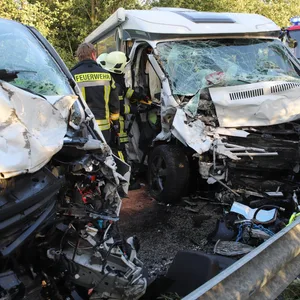 Feuerwehrleute zwischen den zwei sehr beschädigten Fahrzeugen.