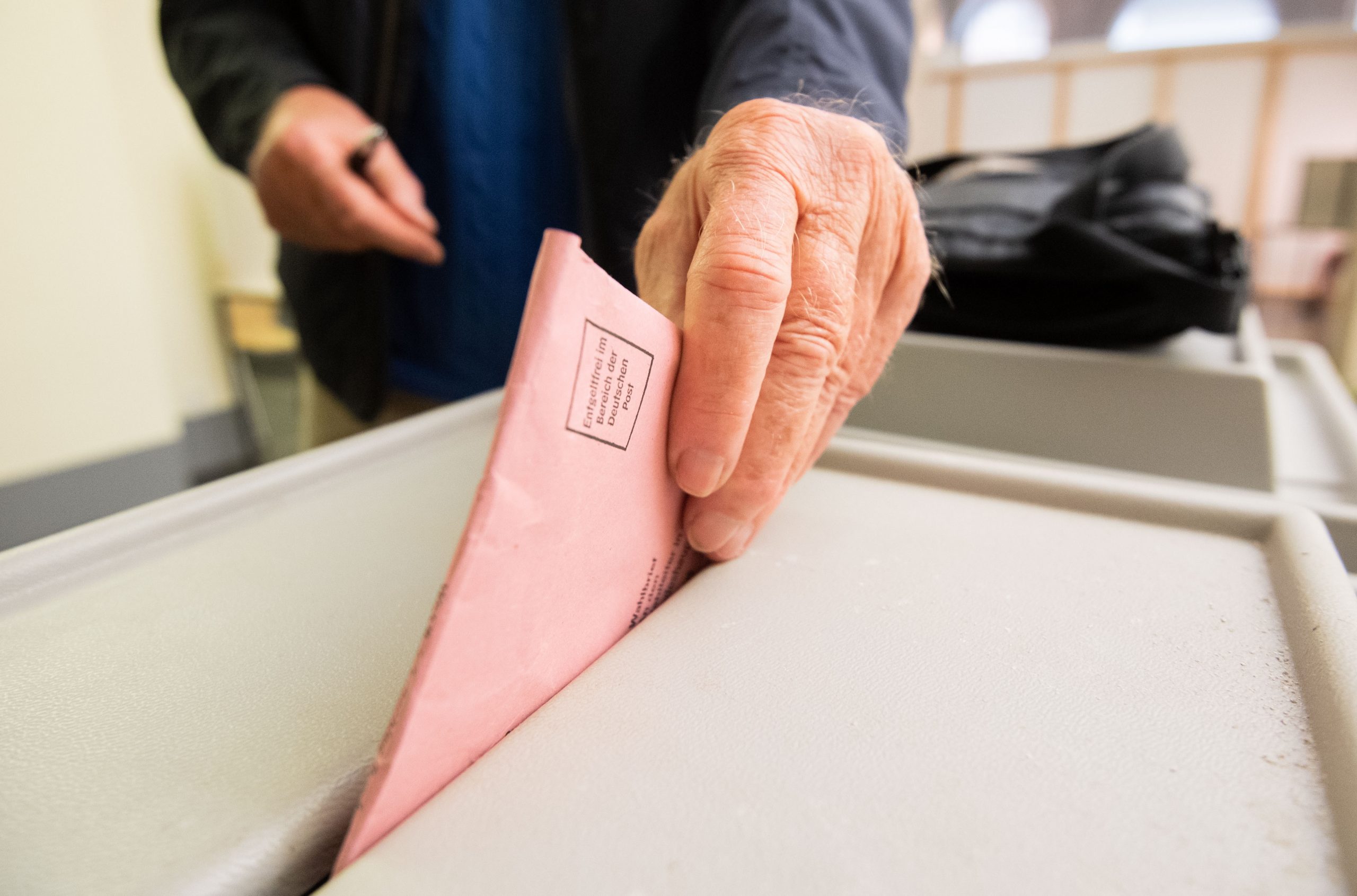 Älterer Mann wirft Stimmzettel in die Wahlurne.