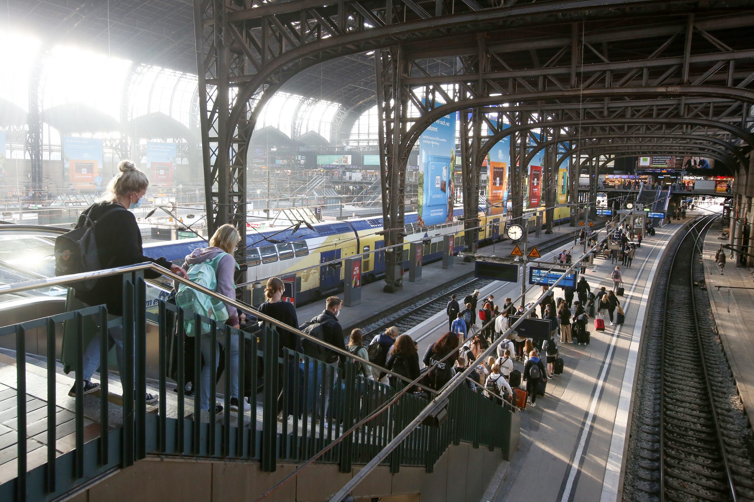 Reisende gehen im Hauptbahnhof auf einen Bahnsteig