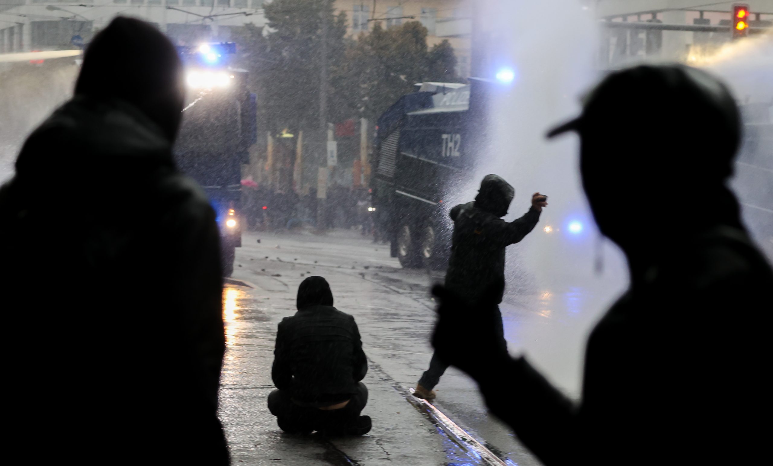 Linke Demonstranten werfen Steine auf Wasserwerfer während Ausschreitungen.