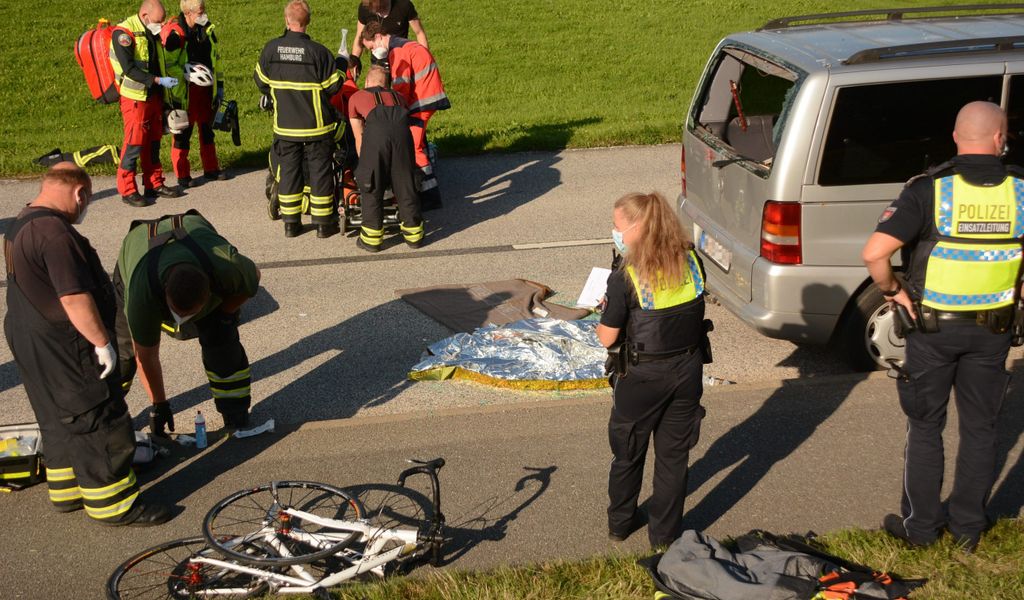 Rettungskräfte um eine Person, Rückscheibe eines Autos zerstört, Fahrrad kaputt am Boden