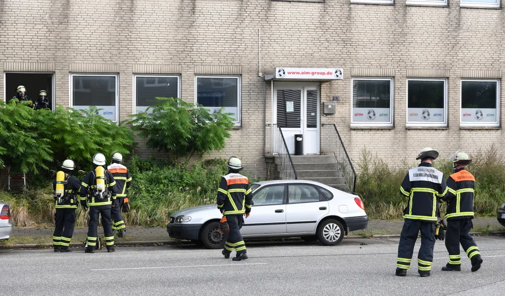 Mehrere Feuerwehrleute stehen vor einem Bürogebäude in Hamm