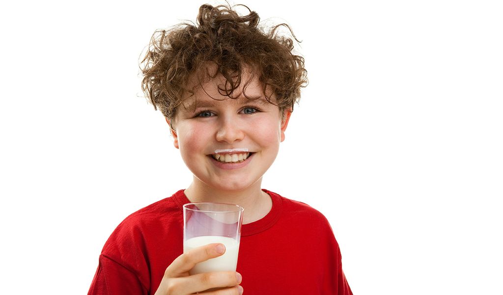 Lachender Junge trinkt Milch