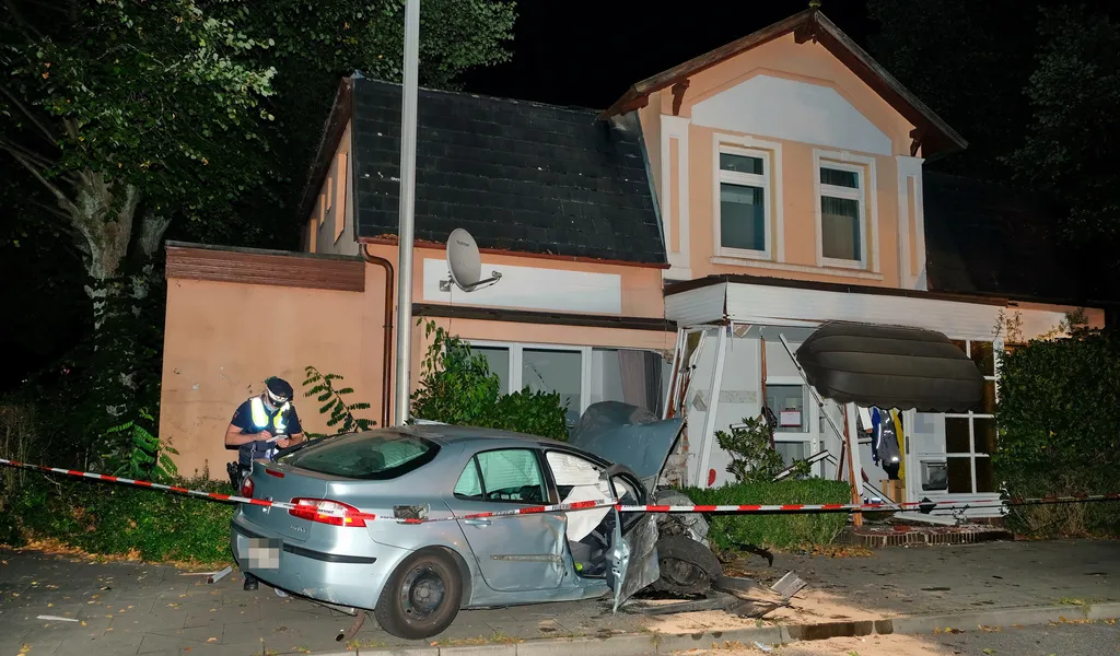 Ein Polizist vor dem Renault Laguna und dem für unbewohnbar erklärten Haus.