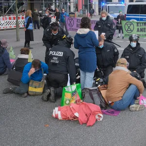 Polizisten entfernen den Kleber von den Händen der Aktivisten.