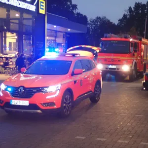 Rettungsfahrzeuge stehen auf einem Parkplatz vor dem Supermarkt