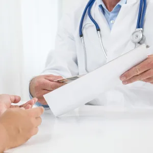 Ein Arzt reicht einer Patientin ein Papier
