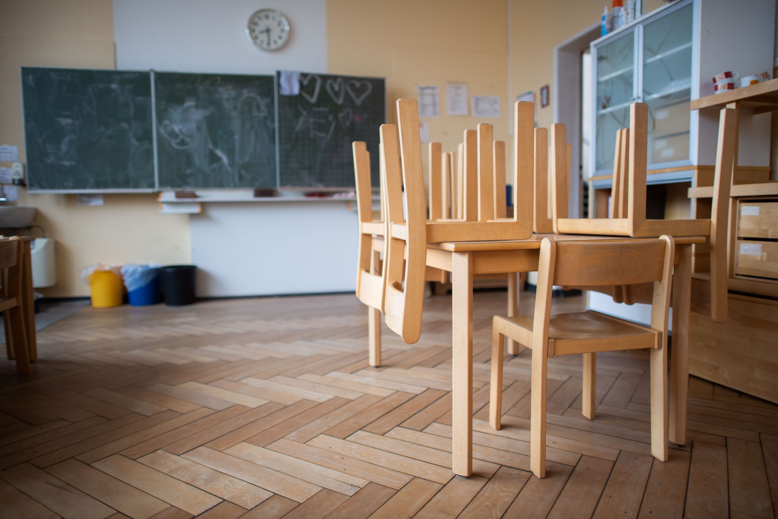 Stühle sind auf Tischen gestapelt in einem Klassenraum.