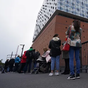 Impfwillige warten in einer langen Schlange vor der Elbphilharmonie auf Einlass.