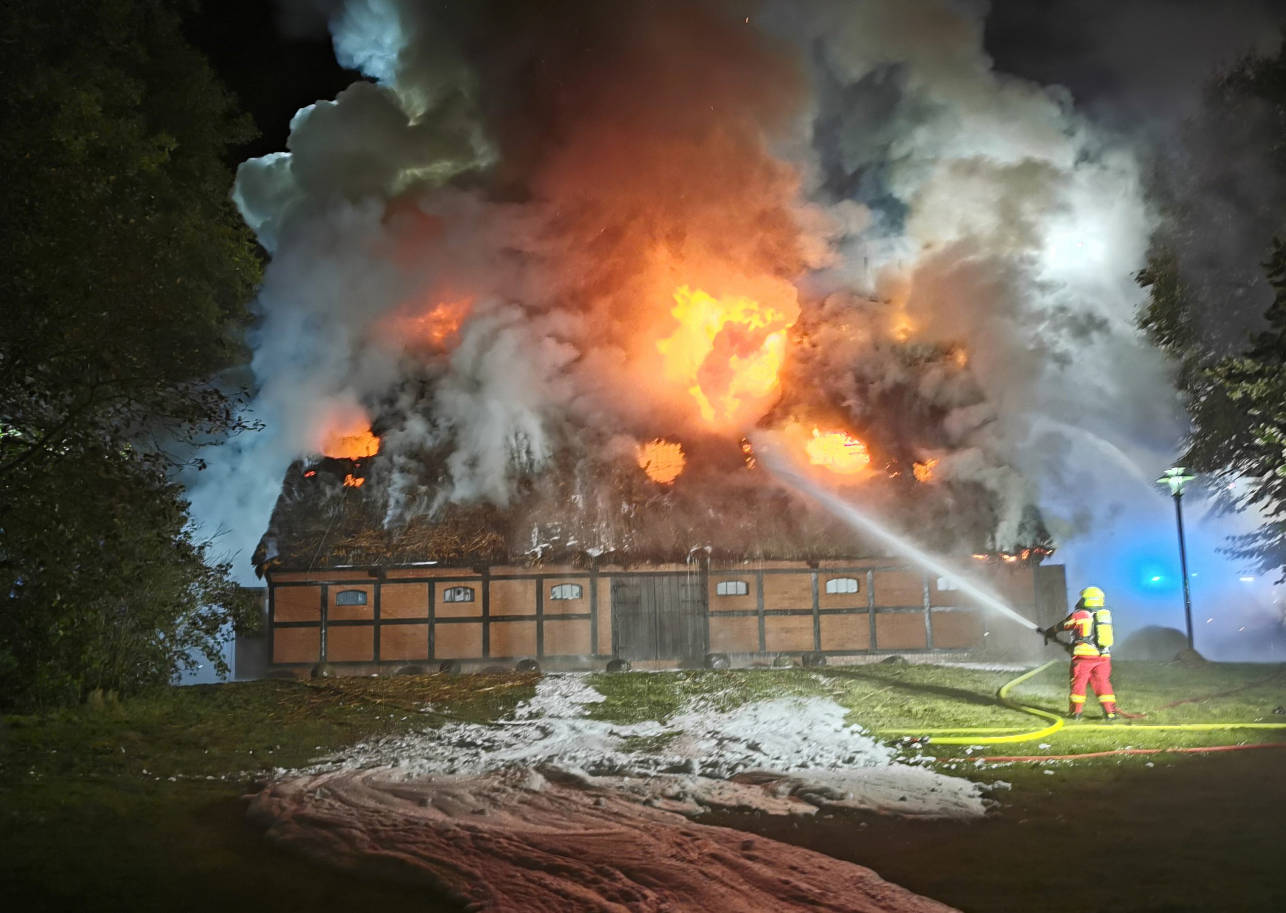 Ein Feuerwehrmann löscht das Feuer, das innerhalb der Scheune wütet.