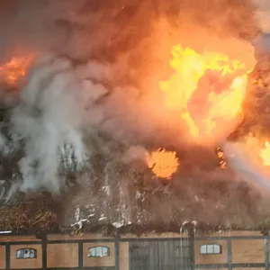 Ein Feuerwehrmann löscht das Feuer, das innerhalb der Scheune wütet.