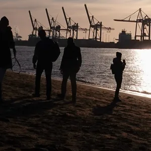 Passanten genießen den strahlenden Sonnenschein am Sonntagmorgen am Elbstrand von Övelgönne.