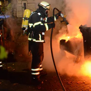 Die Feuerwehr löscht den Brand, der zwei Container zerstörte und einen dritten beschädigte.