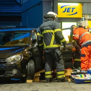 Feuerwehrleute heben den VW Golf an, um die Frau zu befreien.