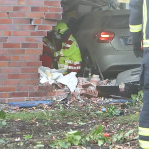Retter der Feuerwehr am Einsatzort. Der Mercedes steht vollständig im Inneren des Hauses.