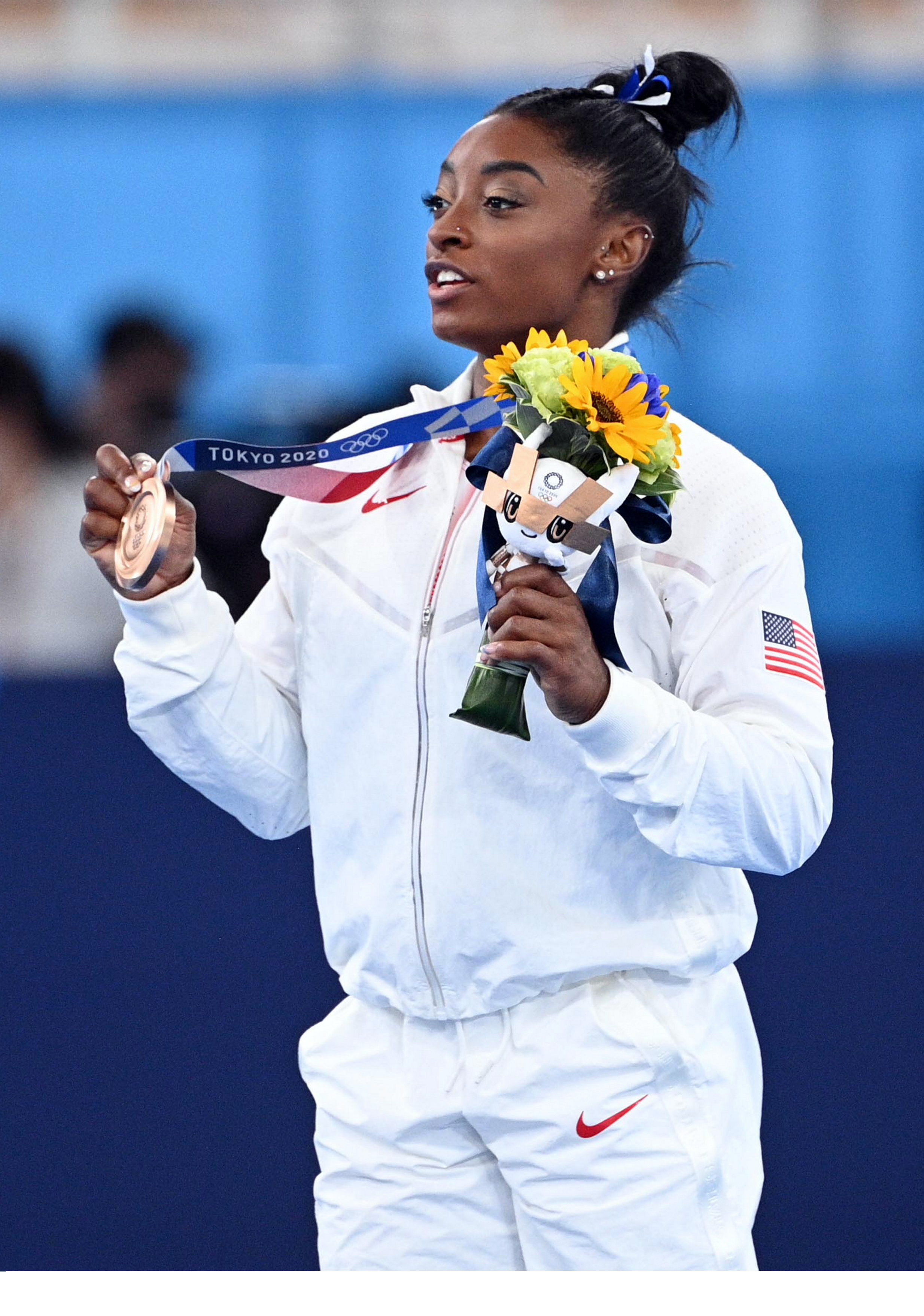 Simone Biles mit Olympia-Medaille und Blumenstrauß