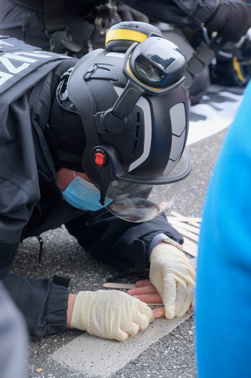 Spezialeinsatzkräfte der Polizei lösen Hand von Asphalt.