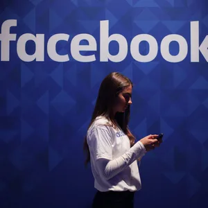 Eine Frau steht vor einem Facebook-Logo (Symbolbild).
