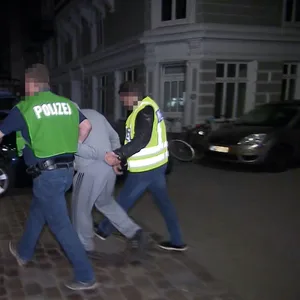 Polizisten führen den jungen Mann ab. Er soll ein IS-Anhänger sein.