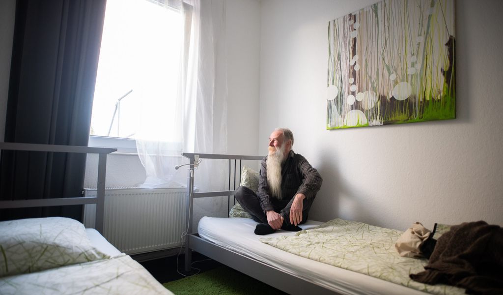Obdachloser sitzt auf einem Hotelbett in Hamburg