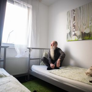 Obdachloser sitzt auf einem Hotelbett in Hamburg