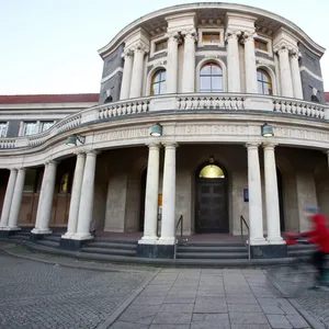 Eine Frau fährt mit einem Fahrrad an dem Hauptgebäude der Universität Hamburg vorbei.
