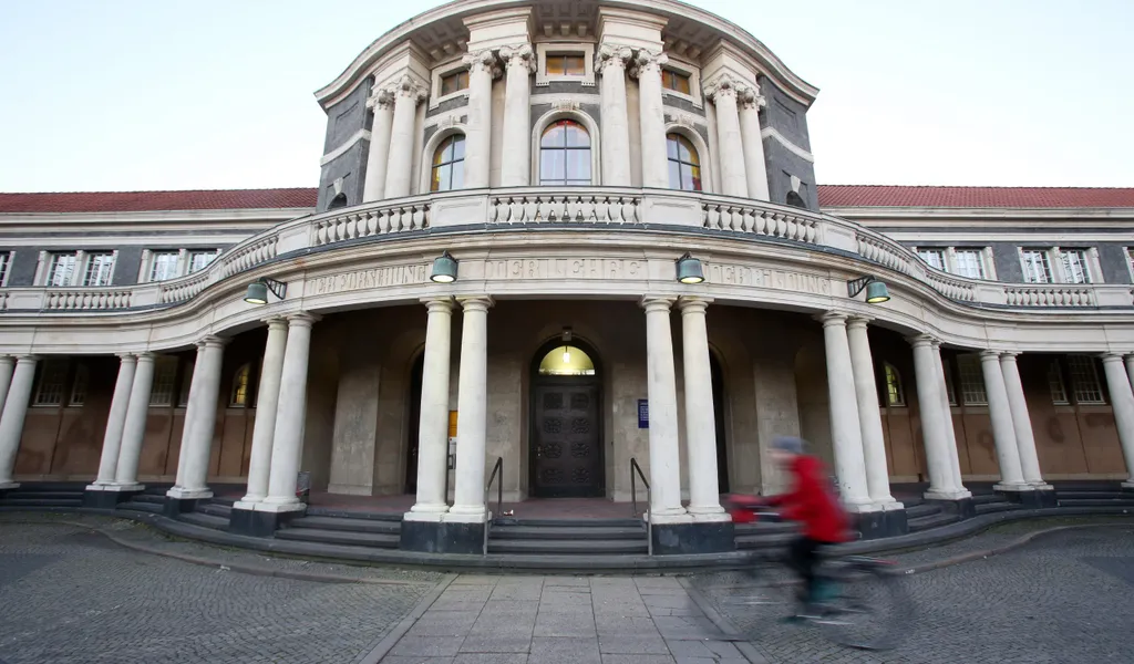 Eine Frau fährt mit einem Fahrrad an dem Hauptgebäude der Universität Hamburg vorbei.