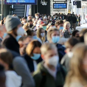Reisende warten im Hauptbahnhof auf einen Zug.