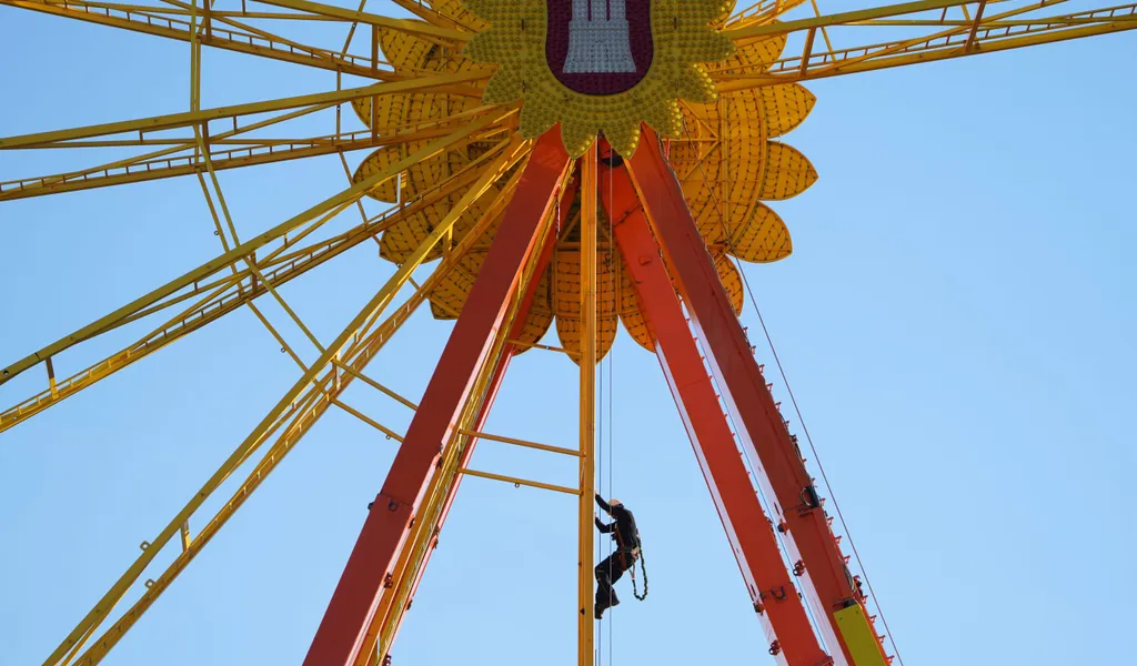 Ein Mitarbeiter klettert während der Aufbauarbeiten im Riesenrad auf dem Heiligengeistfeld.