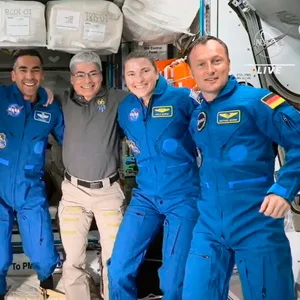 Sieben Personen posieren Arm in Arm für ein Foto auf der Internationalen Raumstation ISS