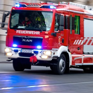 Ein Feuerwehrauto mit eingeschaltetem Blaulicht fährt zum Einsatz.