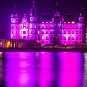 Das Schweriner Schloss wird am Welt-Frühgeborenentag mit lila Licht illuminiert.