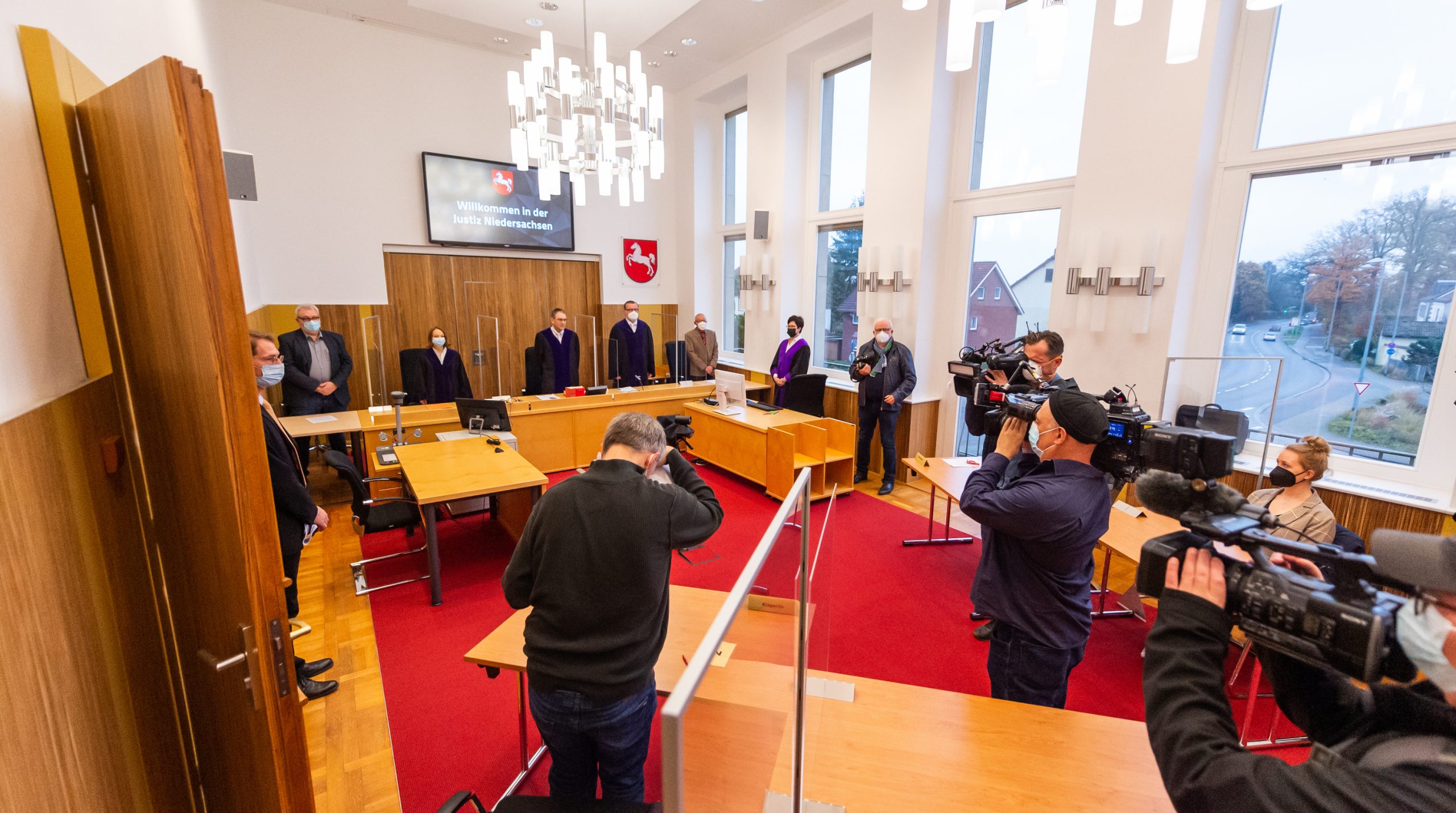 Der Kläger (Mittig) sitzt vor Prozessbeginn im Saal vom Landessozialgericht Niedersachsen-Bremen.