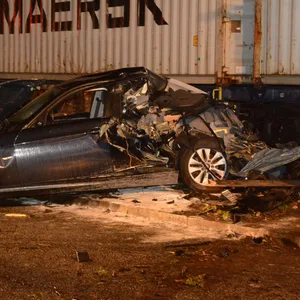 Ein zerstörtes Auto vor einem Güterzug