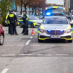 Polizisten vor den am Unfall beteiligten Fahrzeugen.