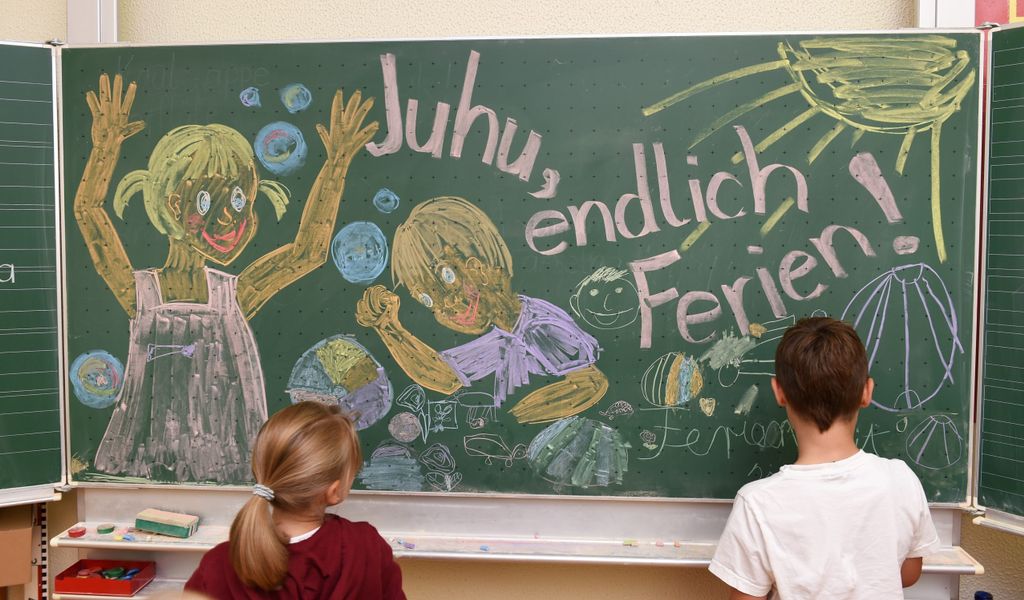 Erst- und Zweitklässler der Grundschule malen am letzten Schultag des Jahres für den Fotografen ein Bild an die Tafel, auf dem «Juhu, endlich Ferien», zu lesen ist.