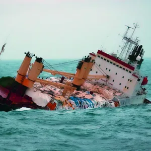 Ein Schiff liegt mit schwerer Schlagseite im Meer.