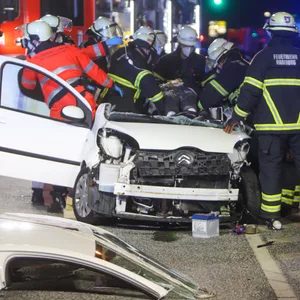 Einsatzkräfte stehen um ein Auto und heben eine Person aus dem Fahrzeug