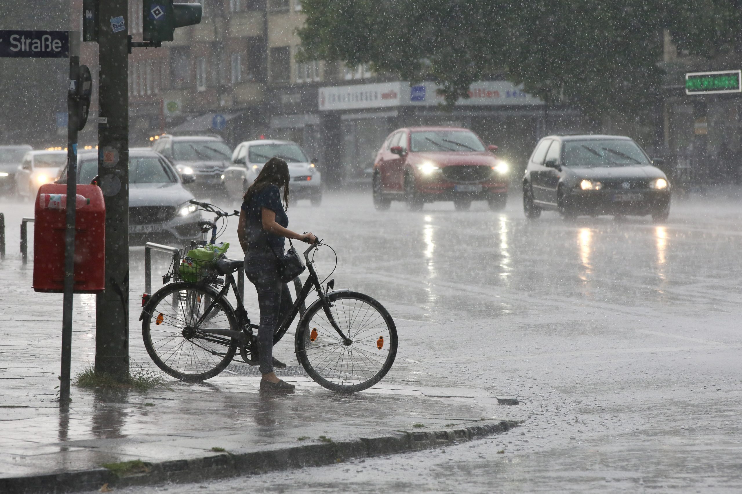 Eine Radfahrerin im Starkregen in Wandsbek im Sommer 2020.