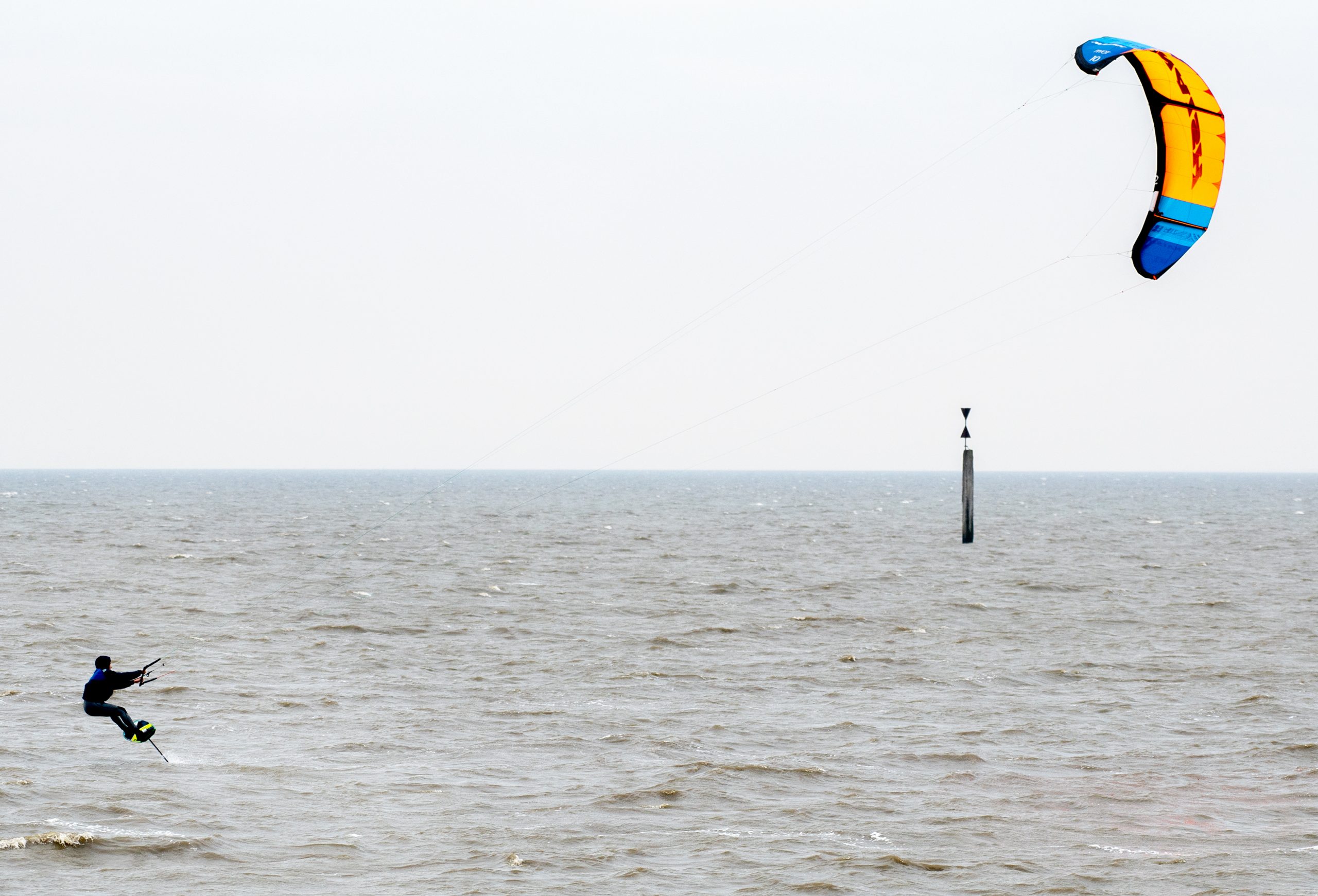Ein Kitesurfer ist bei trübem Wetter auf der Nordsee unterwegs.