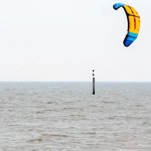 Ein Kitesurfer ist bei trübem Wetter auf der Nordsee unterwegs.