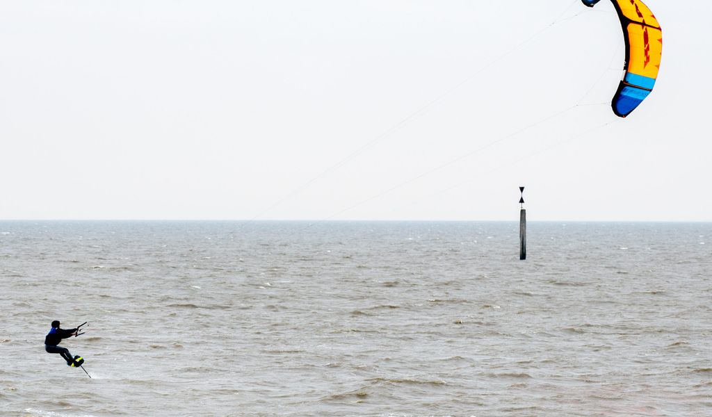 Ein Kitesurfer ist bei trübem Wetter auf der Nordsee unterwegs.