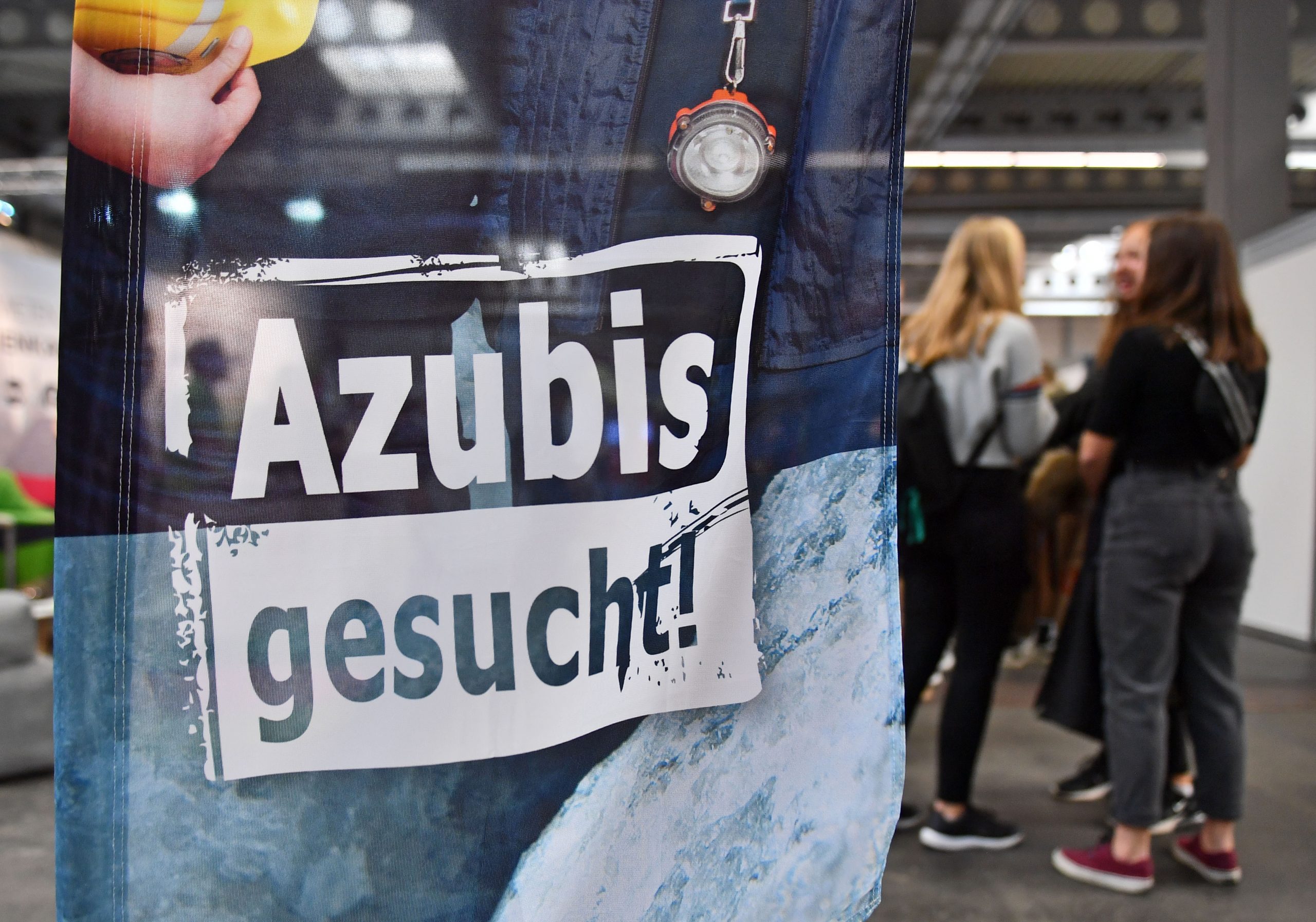 „Azubis gesucht“ steht auf einem Banner bei einer Berufsorientierungsmesse