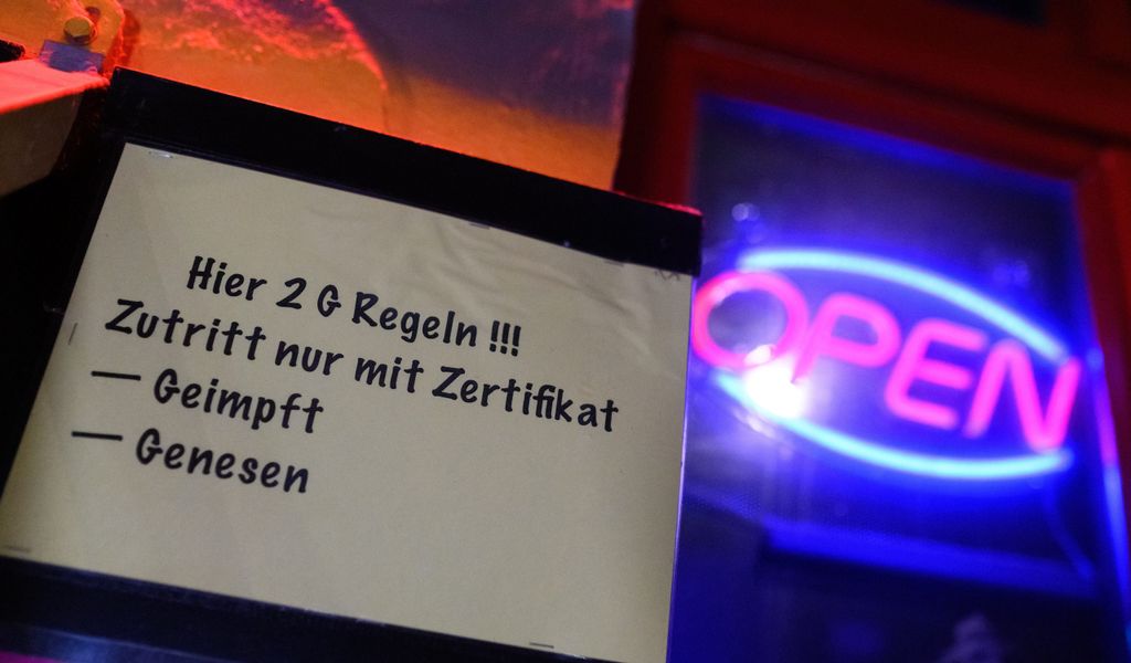 «Hier 2G Regeln !!! Zutritt nur mit Zertifikat - Geimpft - Genesen» steht auf einem Zettel am Eingangs eines Lokals in St. Pauli neben einem «Open»-Leuchtschild.